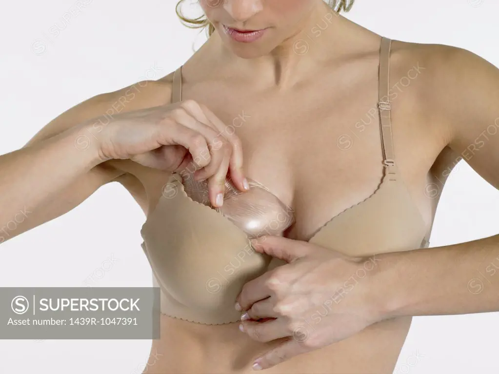 Woman putting breast enhancer in bra