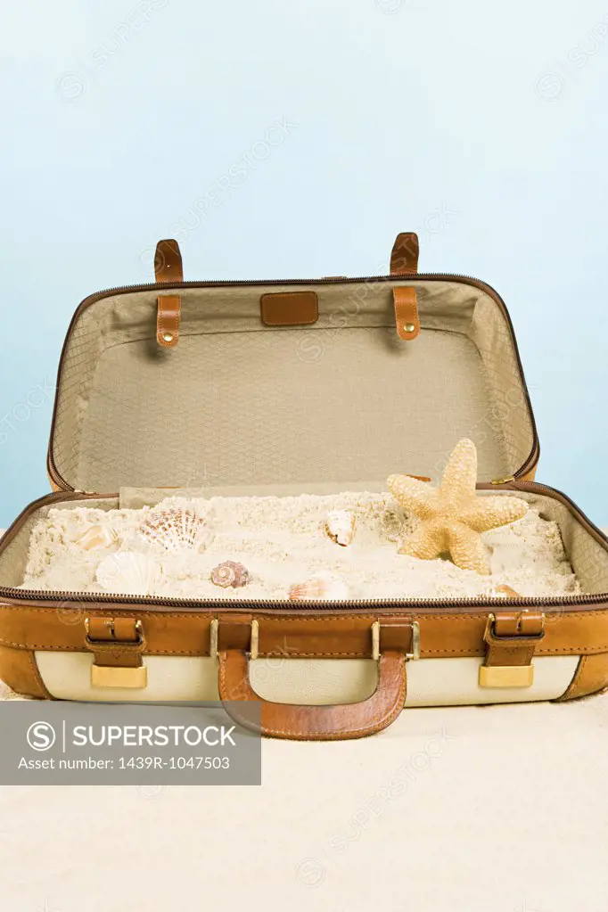 Starfish shells and sand in a suitcase