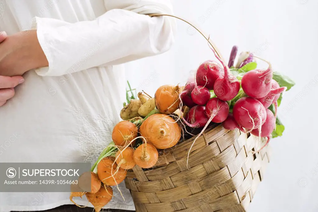 Woman holding basket of beetroot and radishes