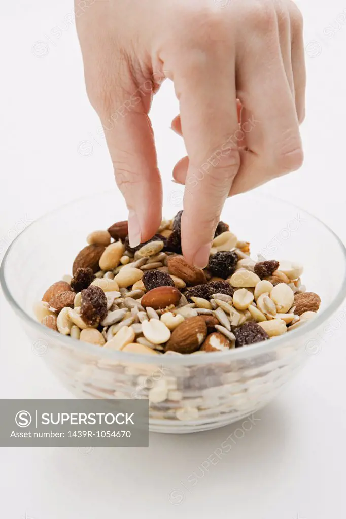 Young woman picking at a bowl of nuts