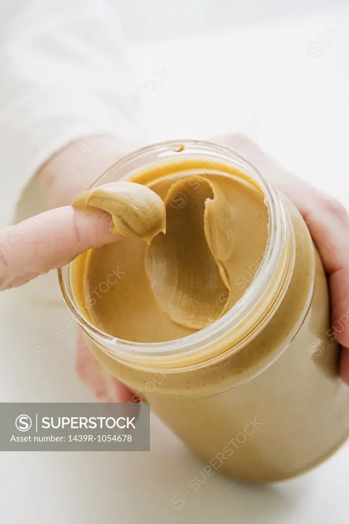 Woman scooping peanut butter from jar