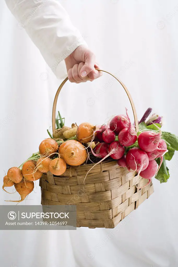 Woman holding basket of beetroot and radishes