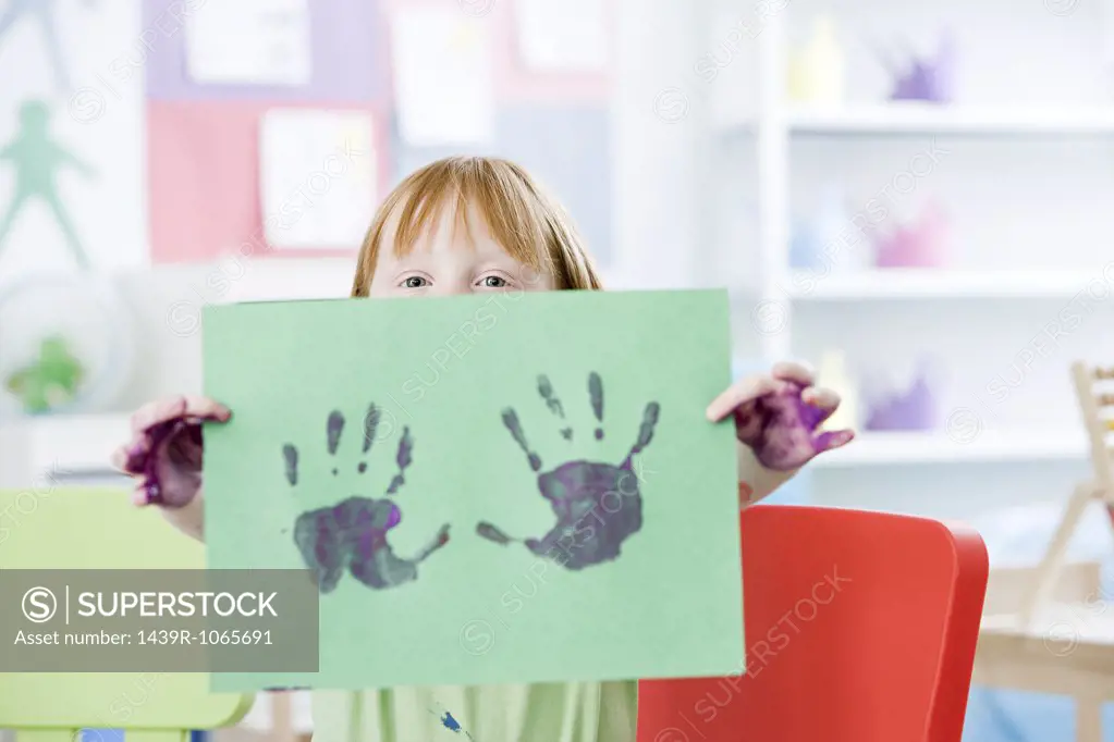 Girl holding up a painted hand print