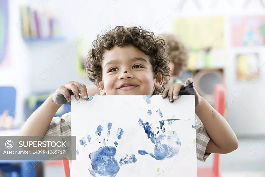 Boy holding up painted hand print