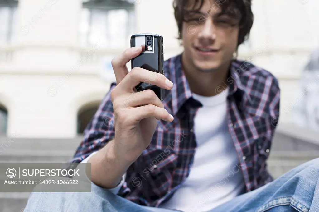 Teenage boy using a camera telephone