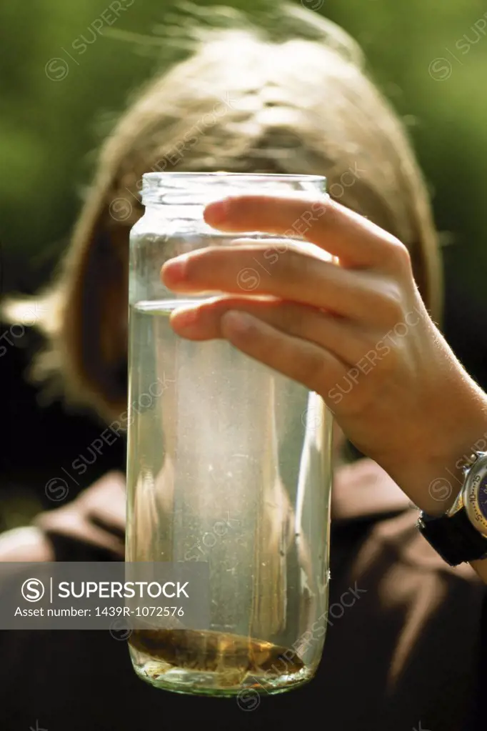 Child holding fish in a jar