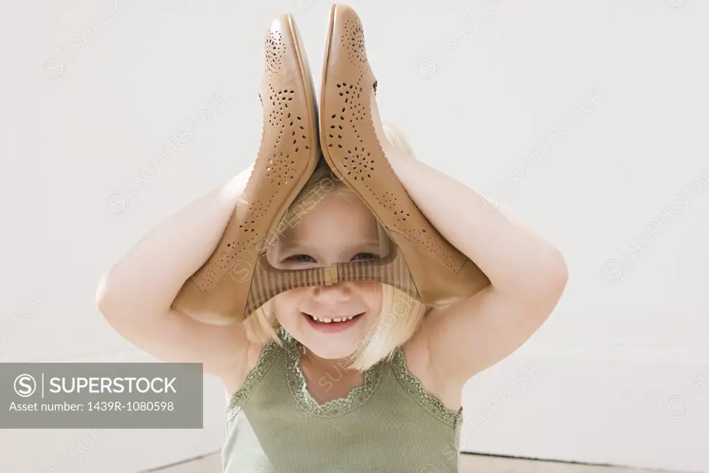 Girl playing with a pair of heeled shoes