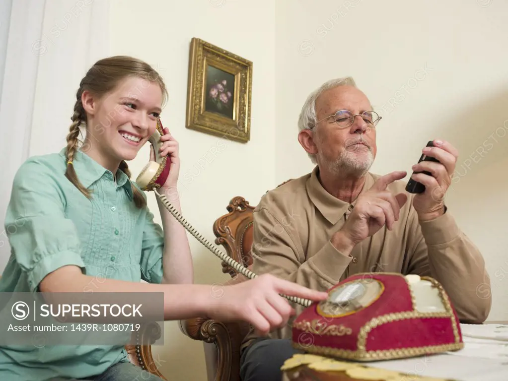 Grandfather and granddaughter using telephones