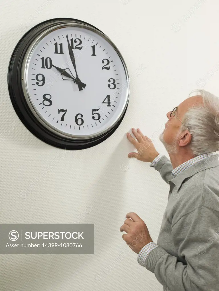 Senior man looking at a large clock