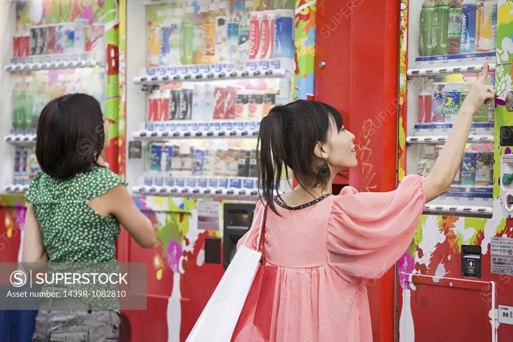 Young women choosing drinks from a vending machine