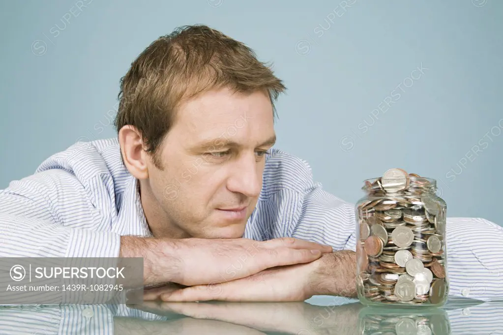 Man looking at jar of coins