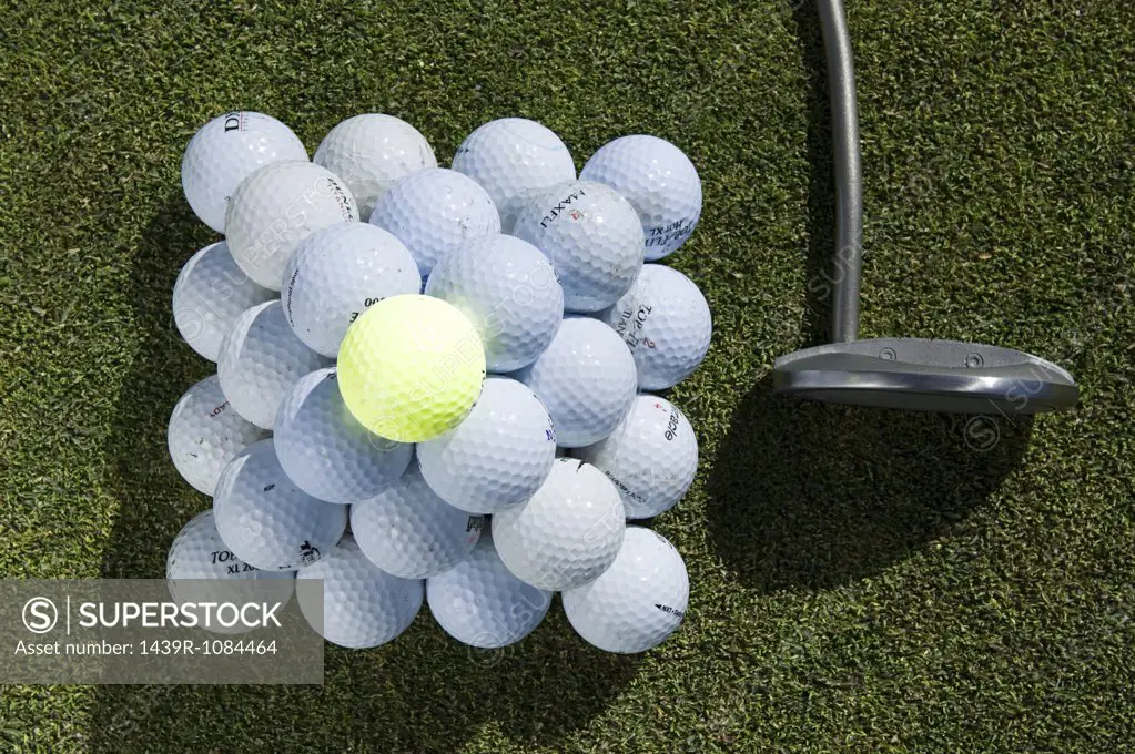 A stack of golf balls and a golf club