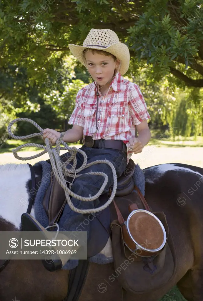 A boy riding a horse and holding a lasso