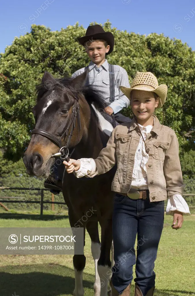 A girl walking a boy on a horse