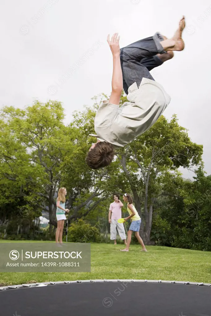 A teenage boy doing somersaults on a trampoline