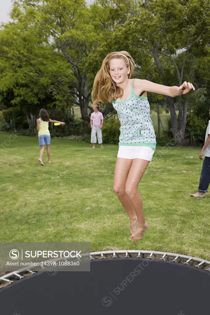 A teenage girl jumping on a trampoline