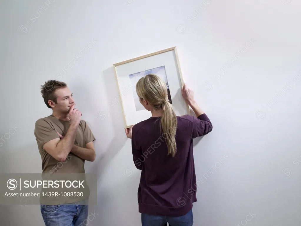 A couple putting art on a wall