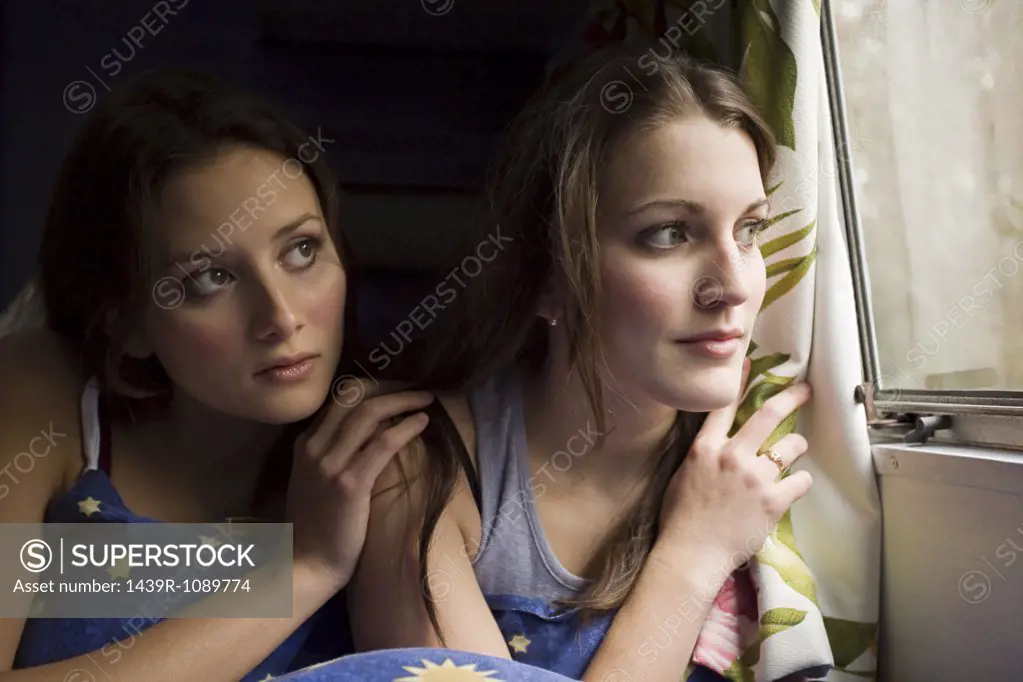 Two teenage girls looking out of a window