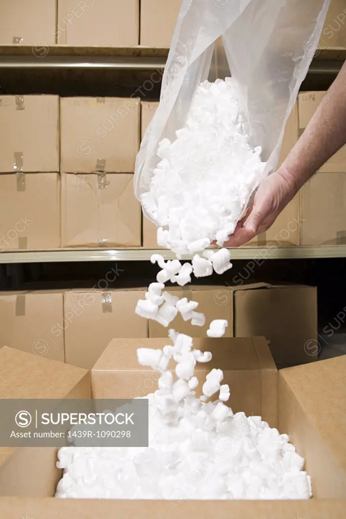 Person putting packing peanuts in box