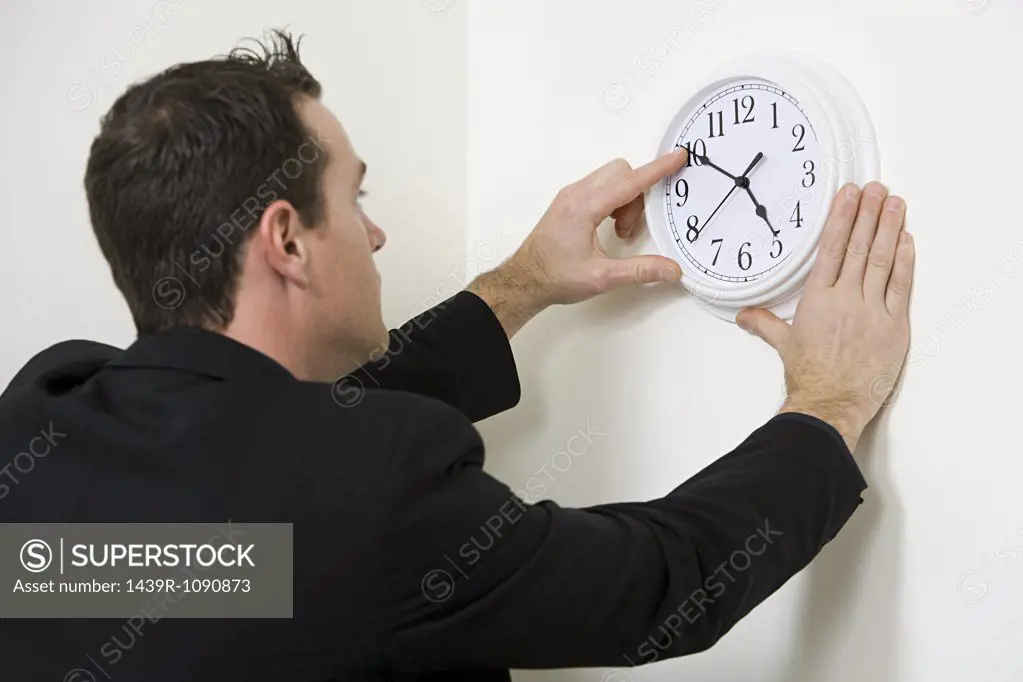 A businessman adjusting the hands on a clock