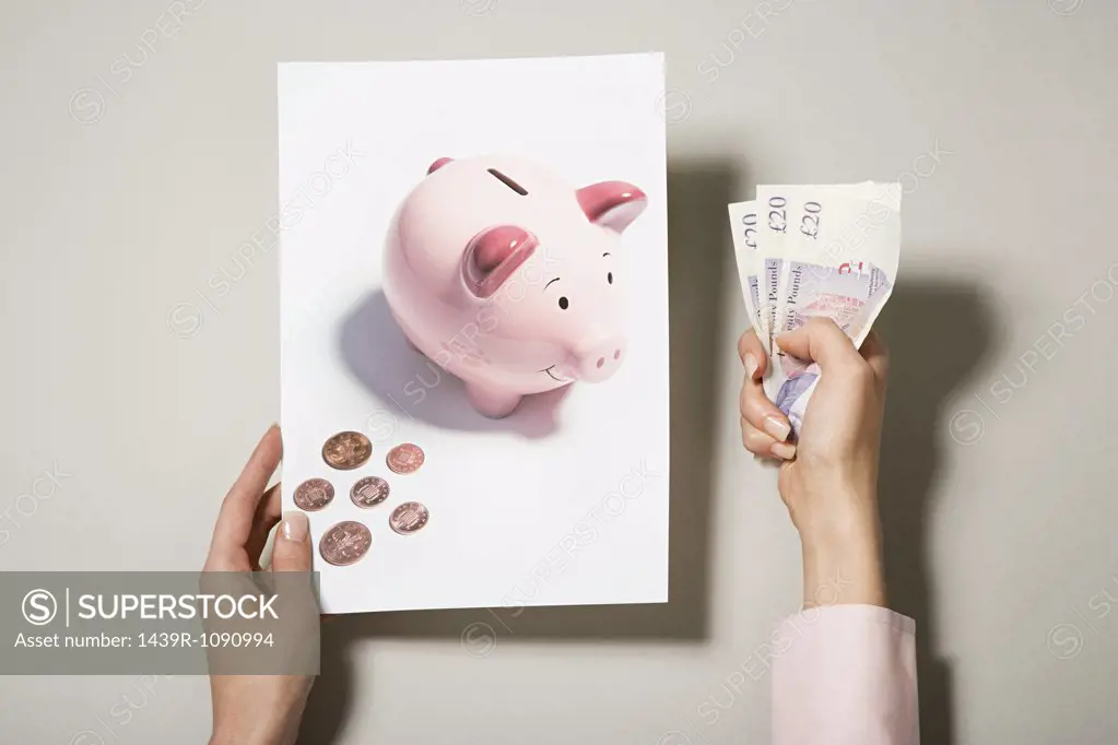 A woman holding a photograph of a piggy bank and money