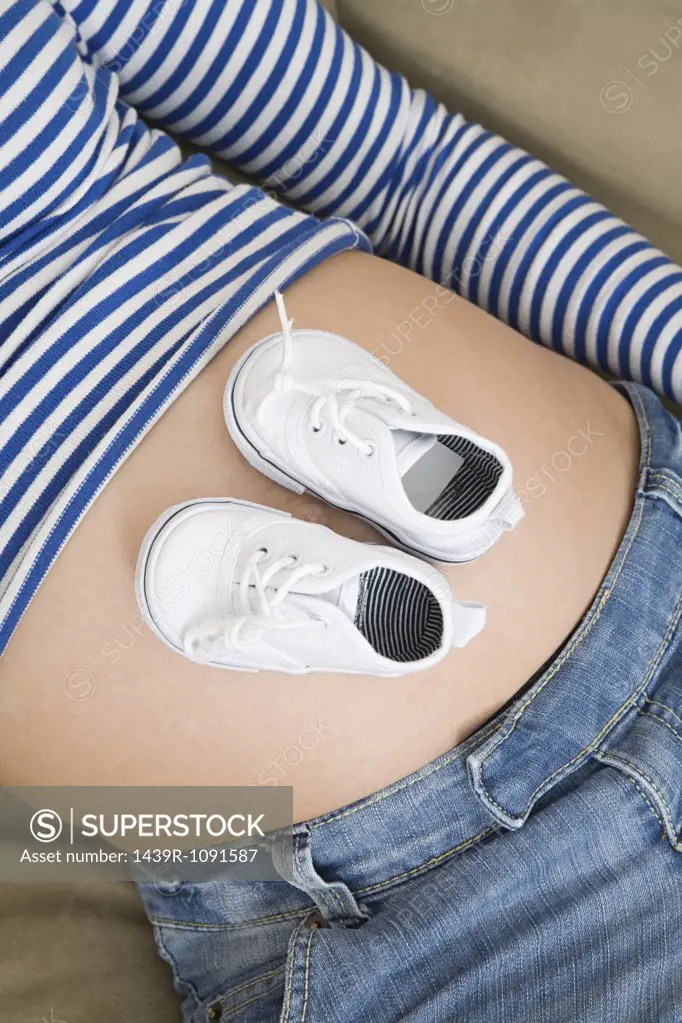 Baby shoes on a pregnant stomach