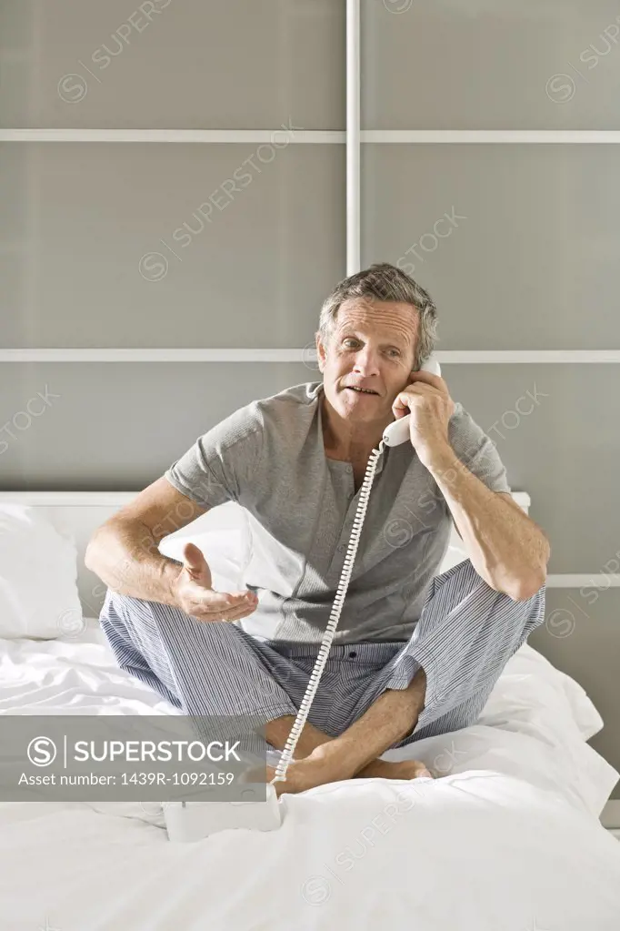 Man on bed using telephone