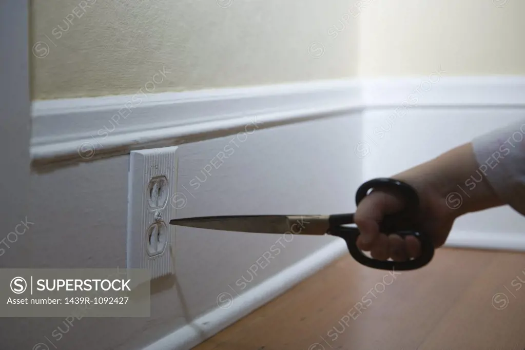 Child poking scissors in electrical socket