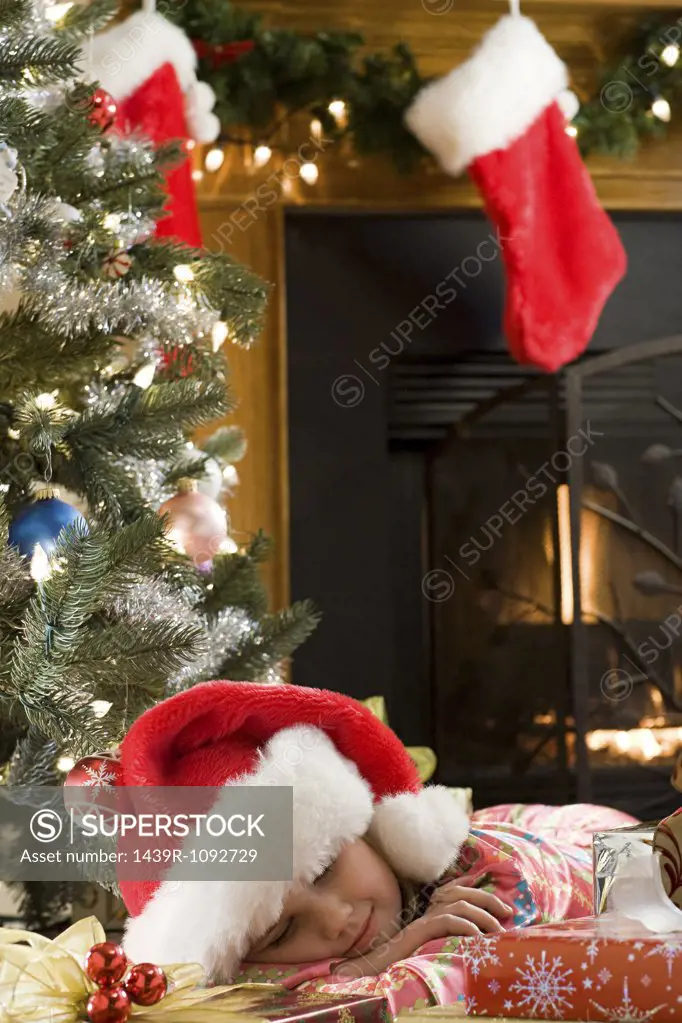 Girl sleeping by christmas gifts
