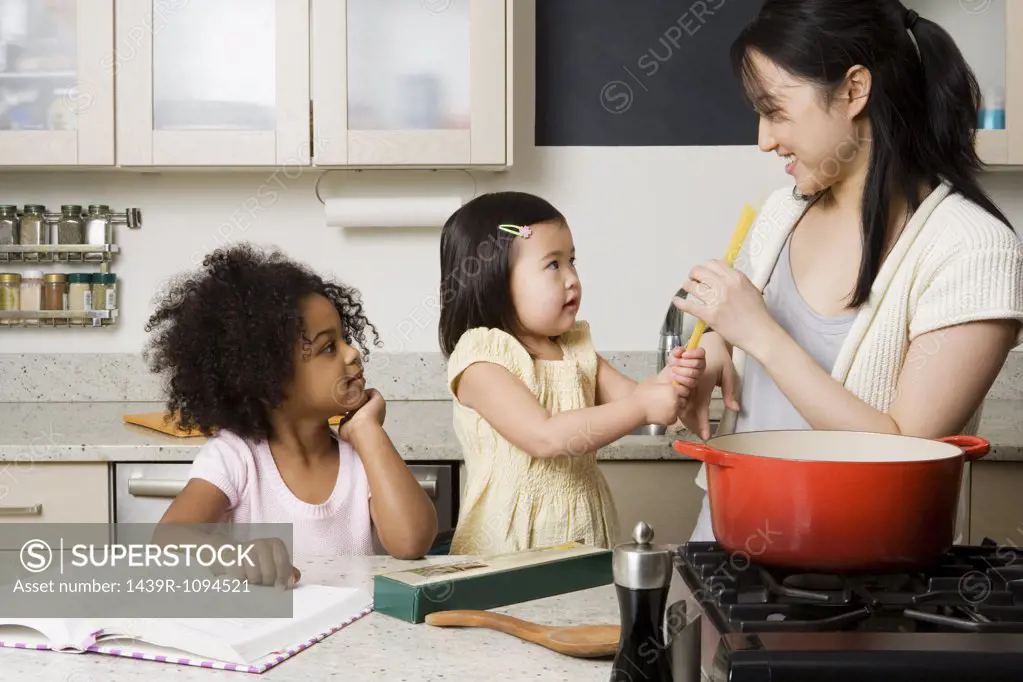 Children helping a woman cook