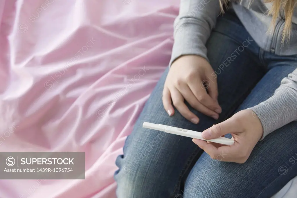 A teenage girl holding a pregnancy test