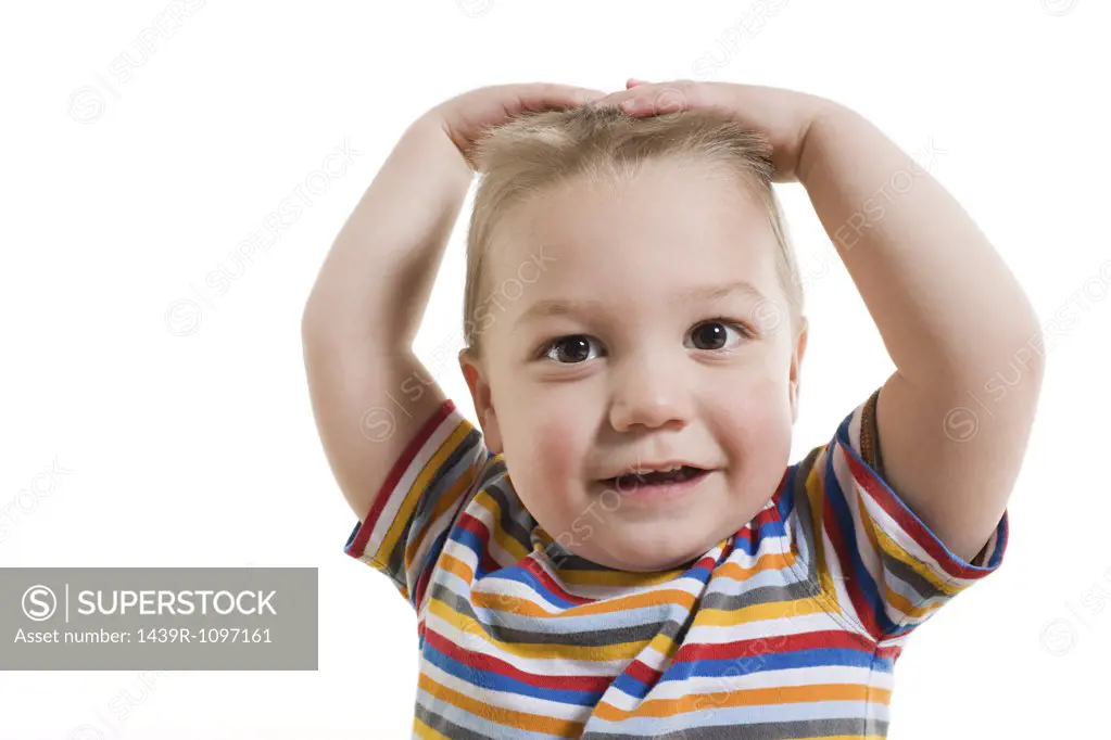 A toddler with his hands on his head