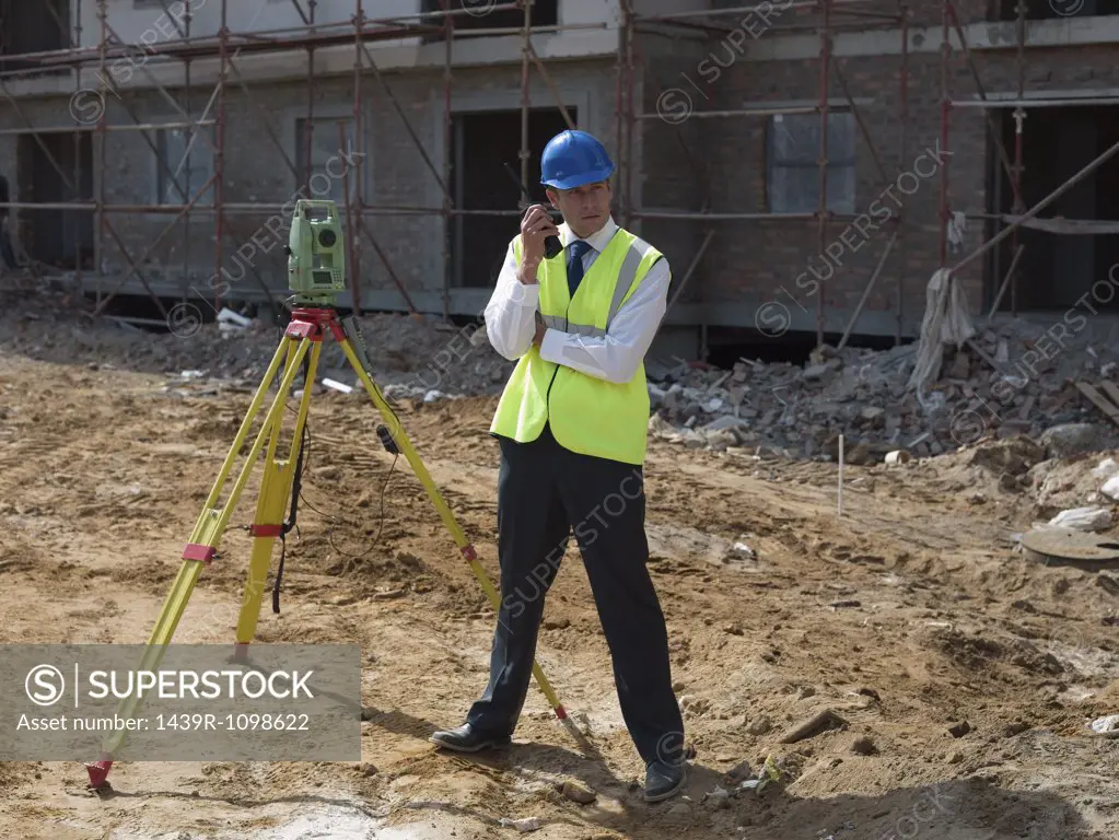 Engineer with theodolite and walkie talkie