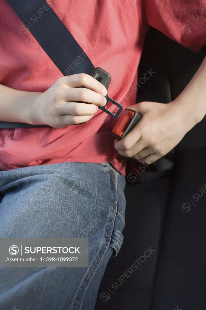 Close up of a boy fastening a seatbelt