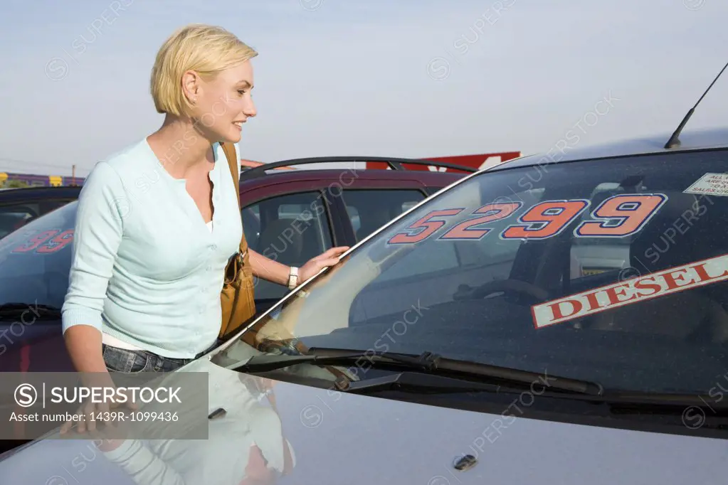 A woman looking at a car at a car dealership