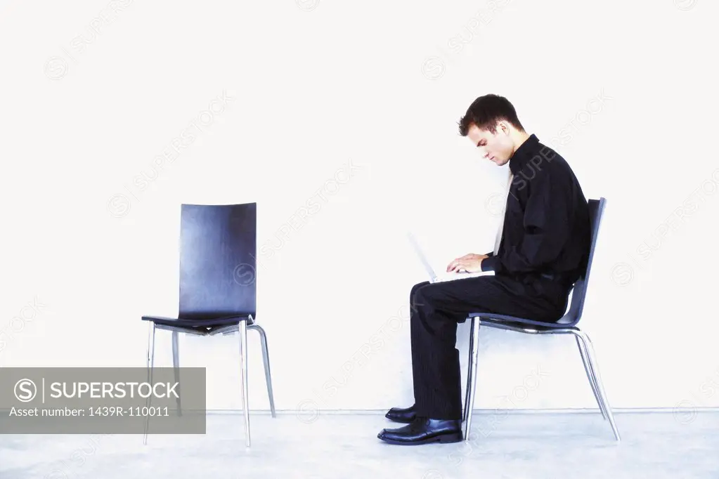 Man sitting on chair with laptop computer