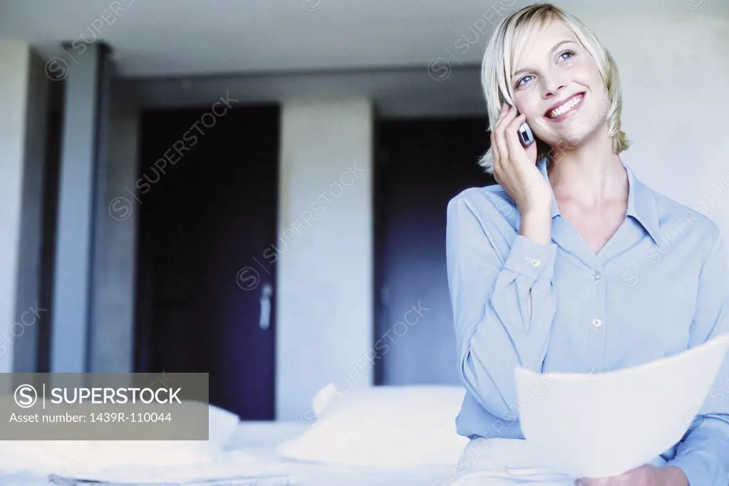 Woman sitting on bed with cellphone