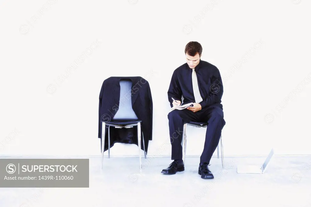 Man sitting on chair writing notes