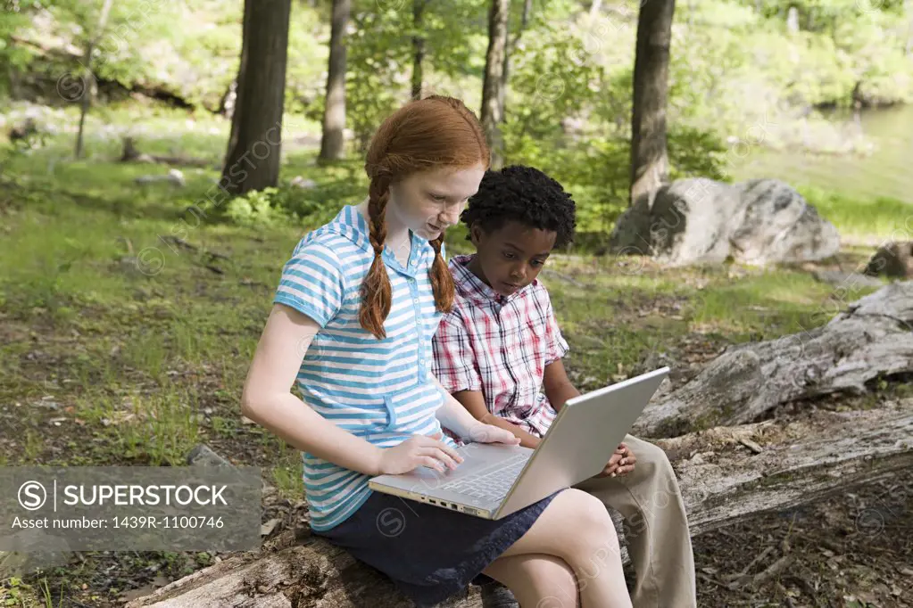 Friends using a laptop in a forest