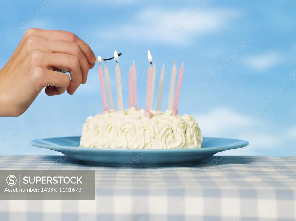 A person lighting matches on a cake