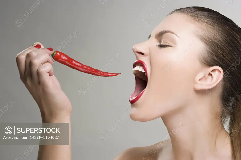 Woman biting a red chili pepper