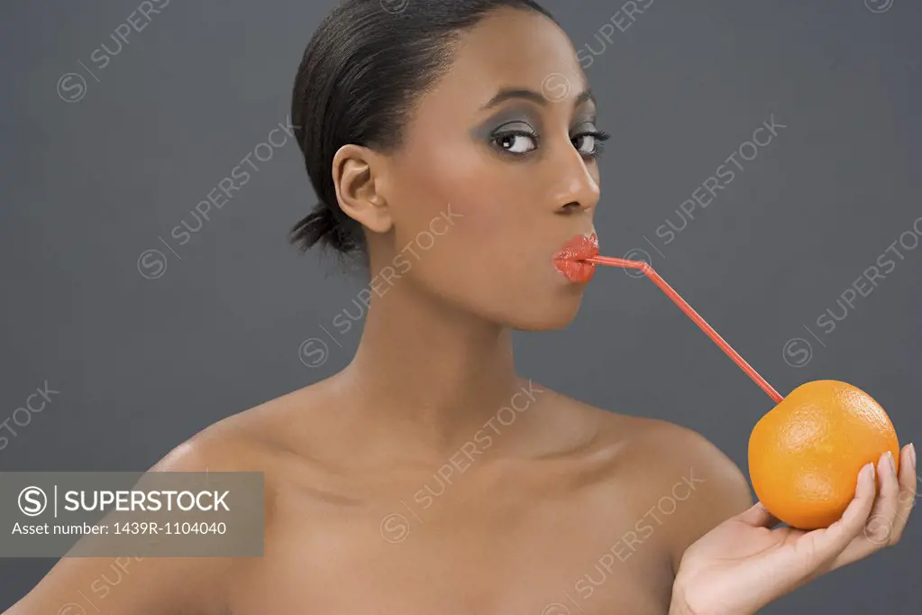 Woman drinking from an orange