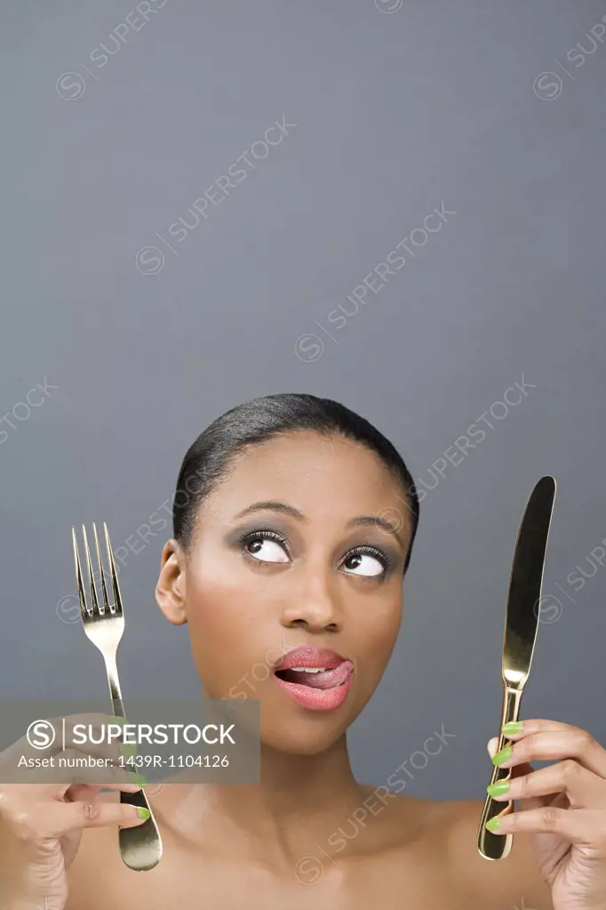 Uncertain looking woman holding cutlery
