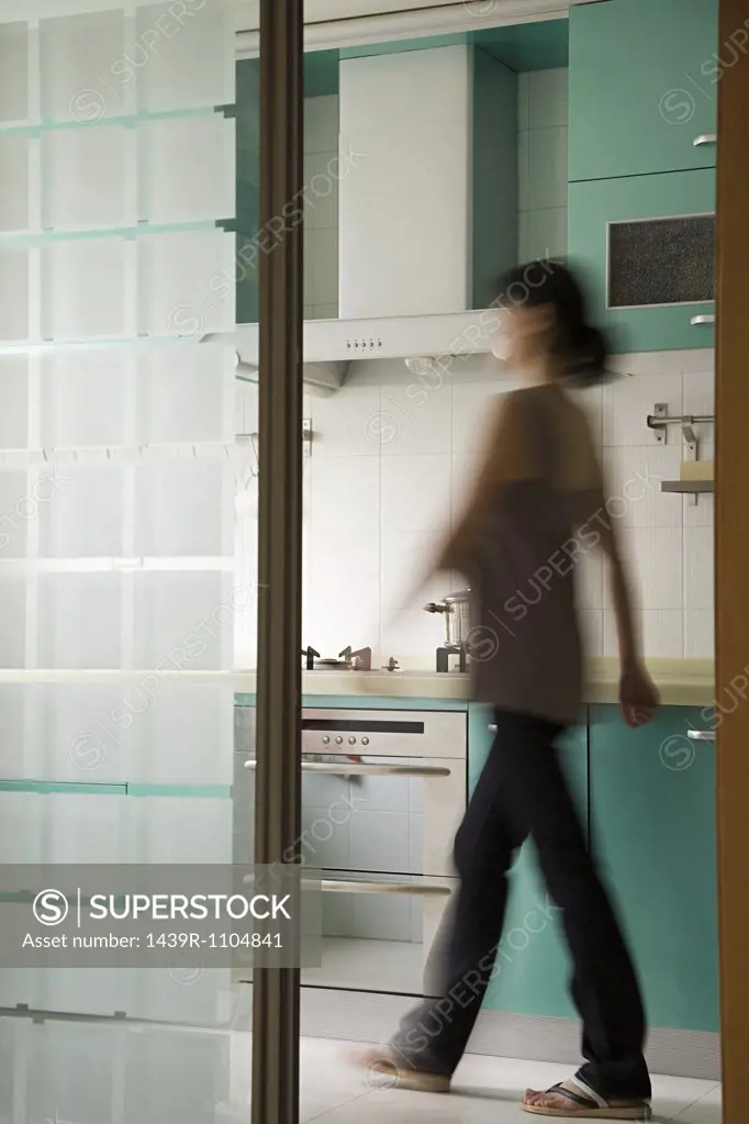 A young woman walking in a kitchen