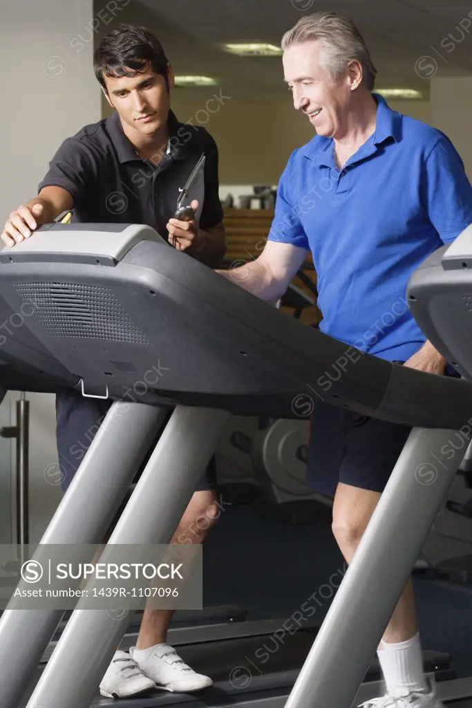 A personal trainer helping a man on a treadmill