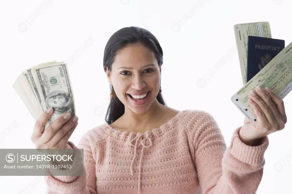 A woman holding a passport airplane tickets and dollars