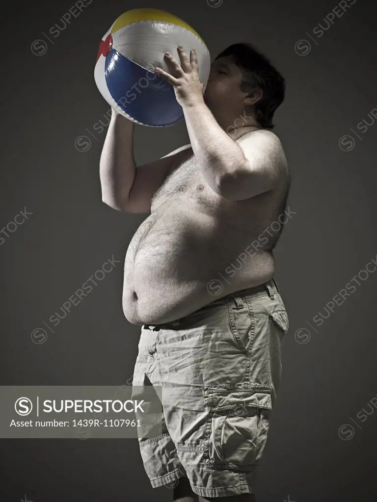 Overweight man blowing up beach ball