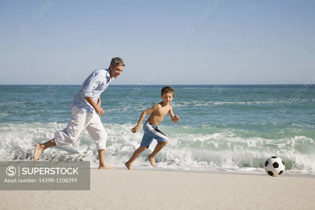 Father and son playing football by the sea