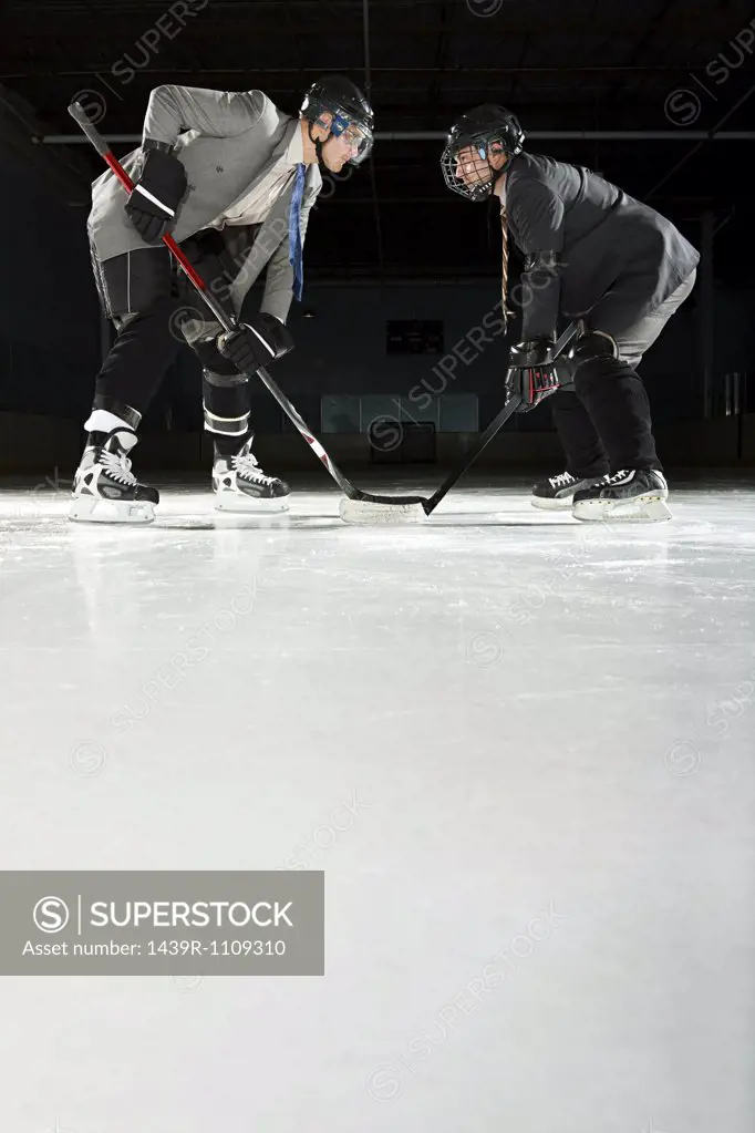 Two businessmen playing ice hockey