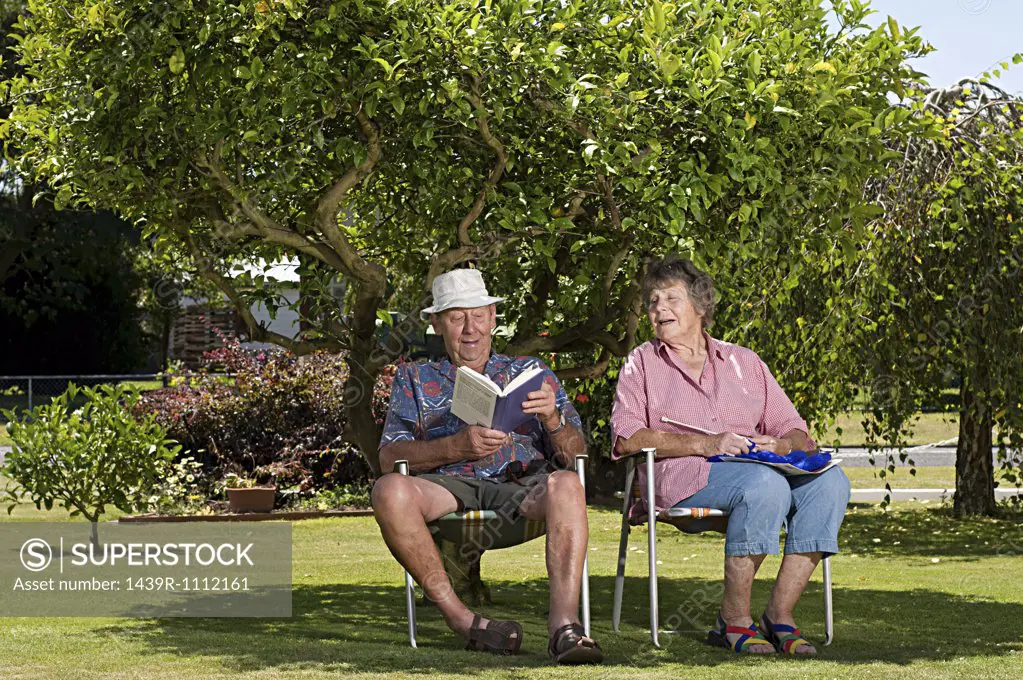 Senior couple relaxing under a tree in the garden